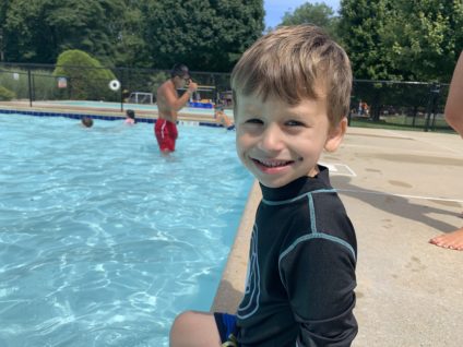 boy sitting on edge of swimming pool